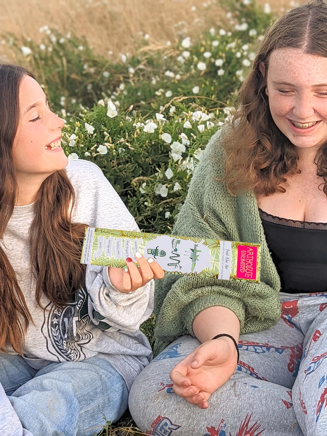 2 girls in a field feel the air well being charity incense sticks with gold & green illustrations