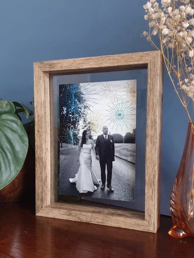 Wedding photo in B&W with hand embroidered sparkly fireworks in double glass frame on desk