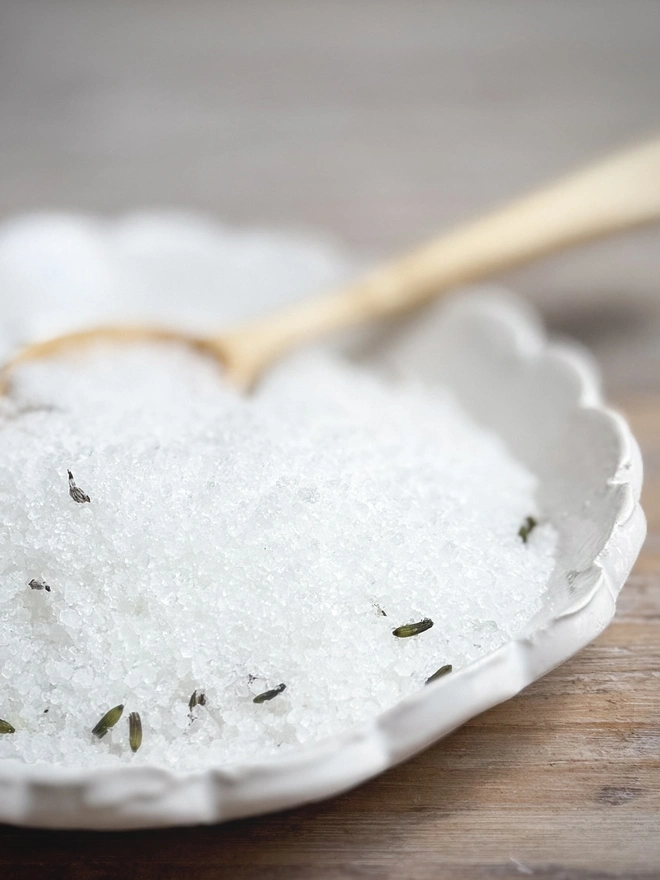 lavender bath salts in a dish with wooden spoon