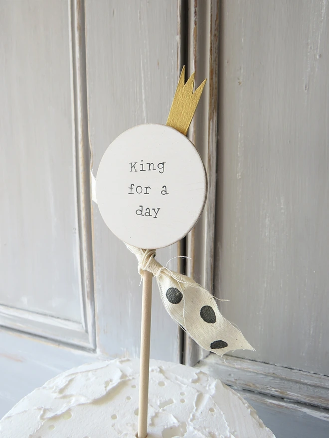 wooden circle shaped cake topper with hand painted message, gold painted crown detail and custom ribbon