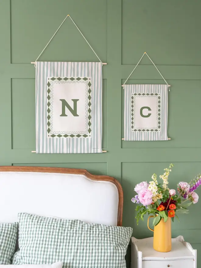 Stripe Initial Fabric Banner, hanging on a green wall. 