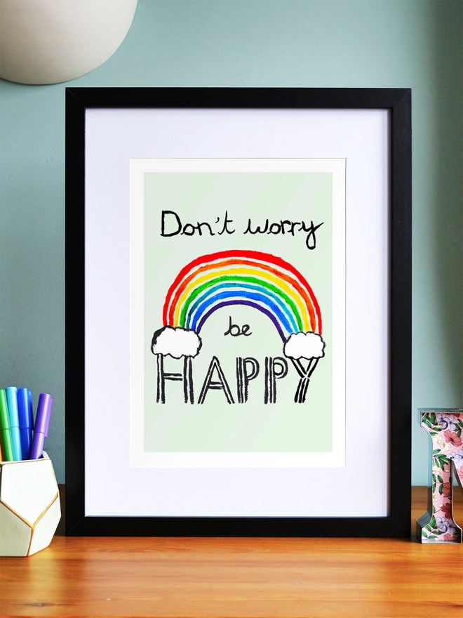 Art print saying 'Don't worry be happy' in a black frame in a child's room
