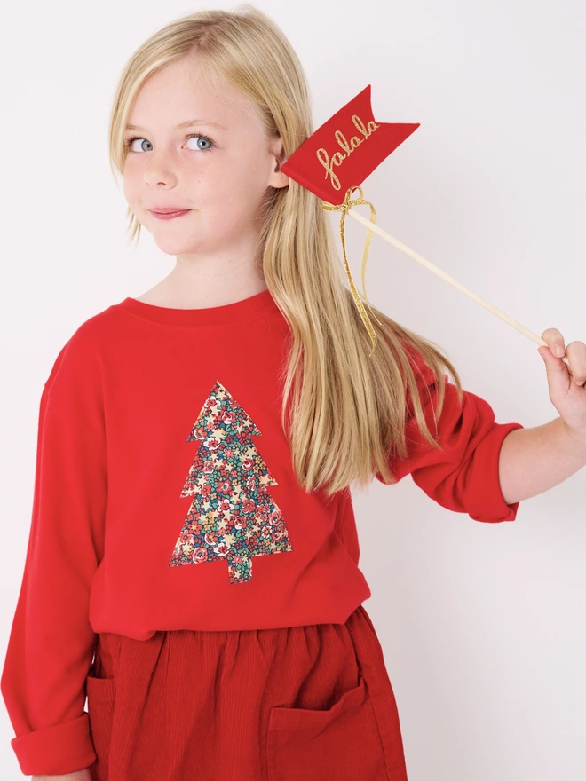 a 5 year old girl wearing a red t-shirt with a liberty floral christmas tree sewn on to the front