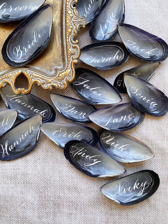 Mussel shell place cards with guest names written in calligraphy 