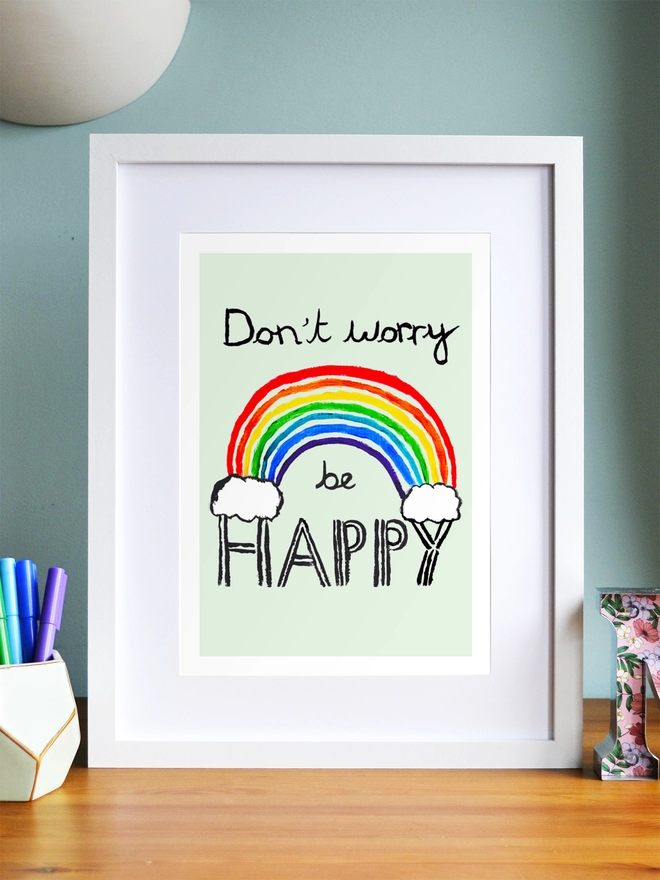 Art print saying 'Don't worry be happy' in a white frame in a child's room