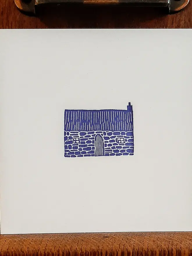Blue Bothy Letterpress Handprinted Greetings Card, a white card with a blue bothy in the centre on a wooden surface. 
