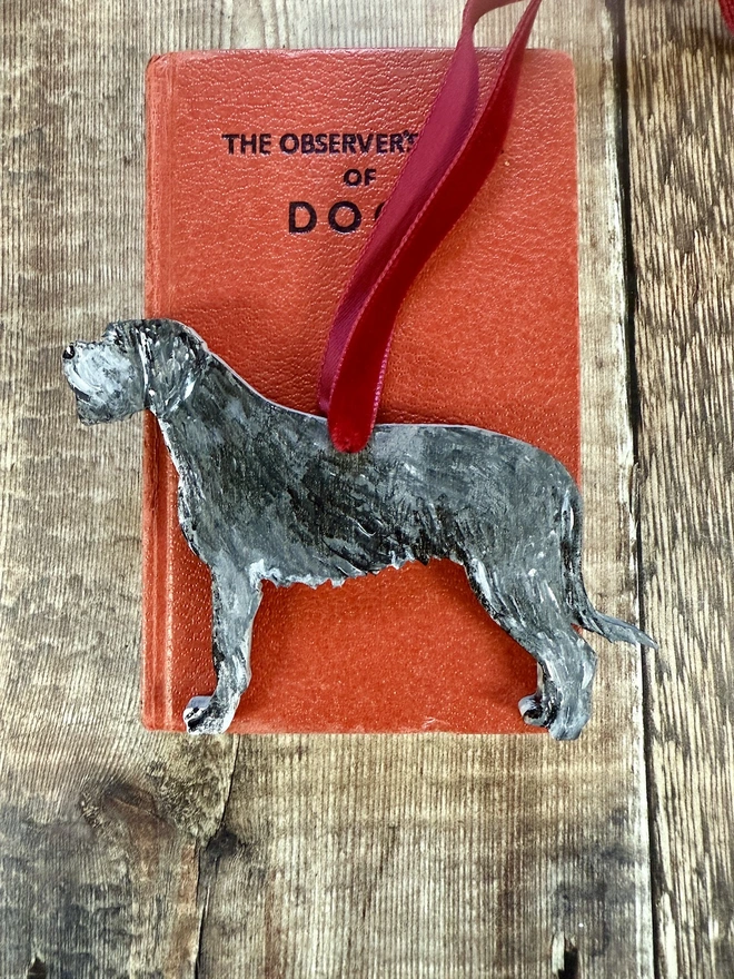Irish Wolfhound Handpainted wooden Christmas Decoration placed on a book about dogs 