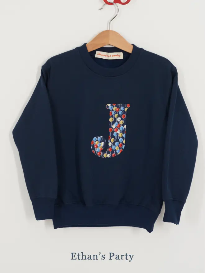 a navy kids sweatshirt with the initial J personalised in balloon liberty print on the front