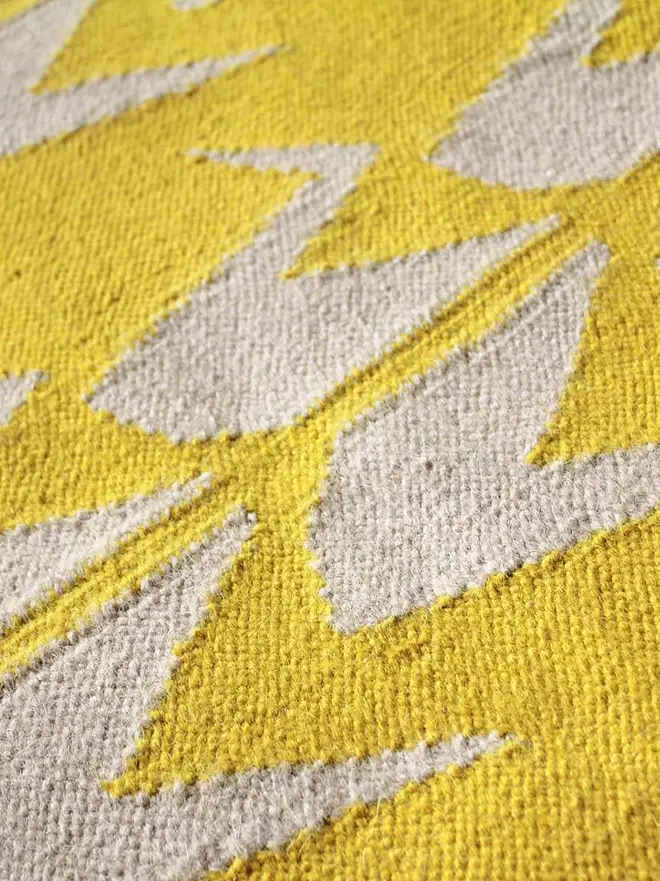 Crane Flatweave Rug, a colourful rug sitting on a plain surface. 