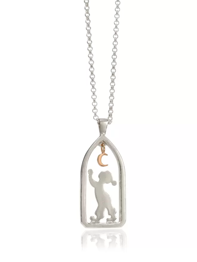 Silver pendant suspended off silver chain showing boy figure reaching for golden suspended crescent moon