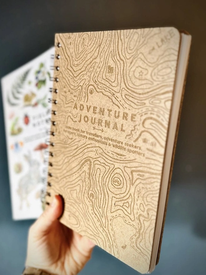 Wooden Hardback Adventure Journal, a person holding an adventure journal in their hands against a blue backdrop. 