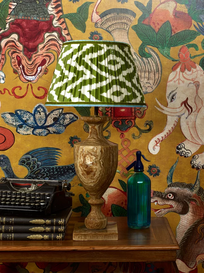 Maximalist Interior Design: Classic Green Silk Ikat Lampshade on Table in Patterned Wallpapered Room