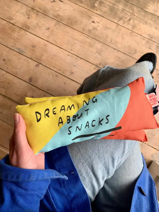 Stack of lavender eye pillows which read 'dreaming about snacks'