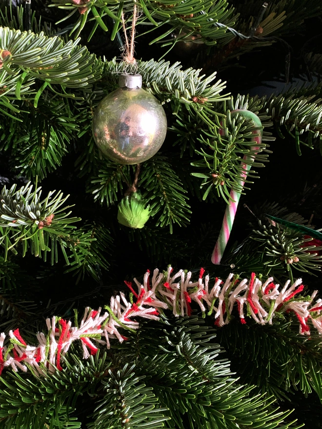 Close up of a real Christmas tree adorned with a vintage silver bauble, candy cane and Candy Cane string tinsel AKA Strinsel