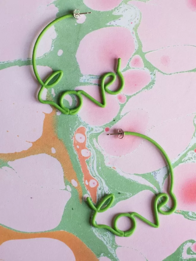 Large green Love Hoops by Zoe Sherwood seen on marble paper.