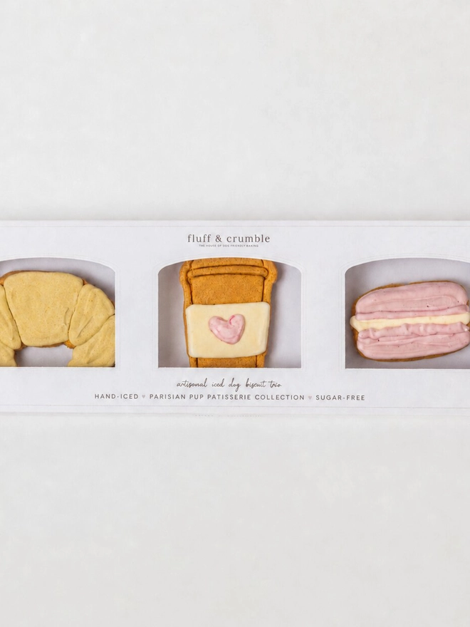 Boxed Parisian Bakery iced dog biscuit trio featuring a croissant, takeaway coffee cup and pink macaron.