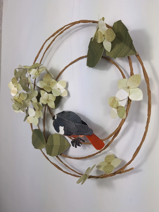 back view of a handmade wall hanging, featuring a redstart bird and green hydrangea flowers