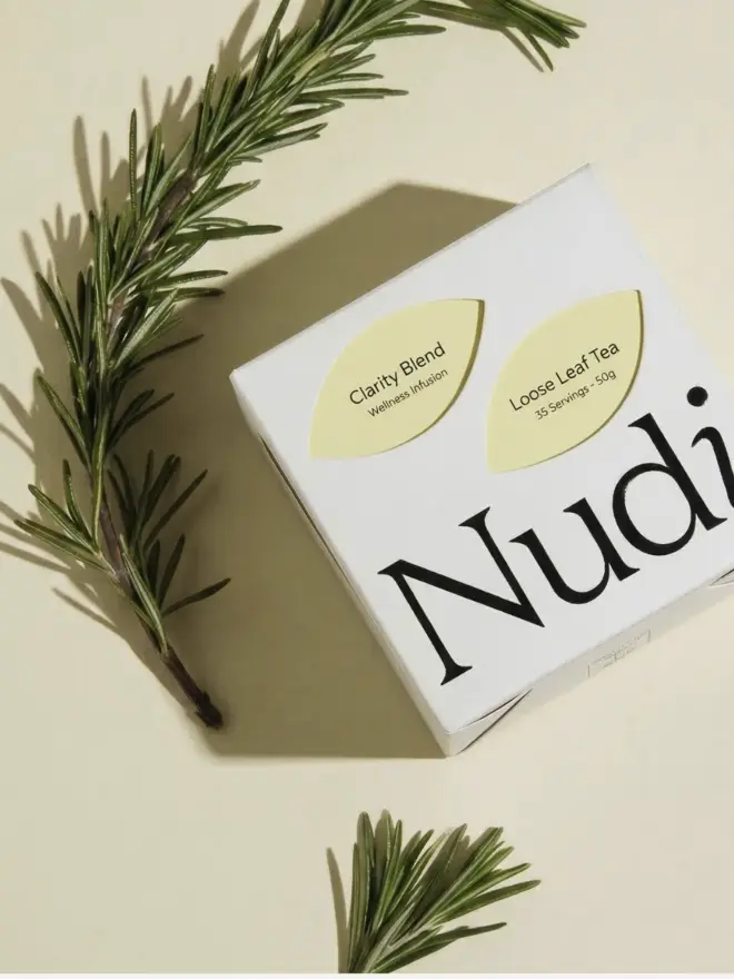 white box of clarity blend tea with yellow leaf design next to sprig of rosemary