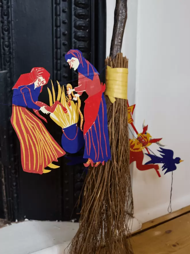 Lifestyle shot of witches and devil peeping out of wooden broomstick