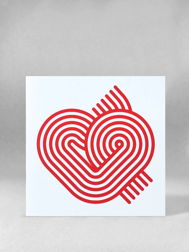 Six magenta swirling stripes create a neat heart-like graphic on the front of this square white card. This studio shot shows the card slightly open on a light grey background.