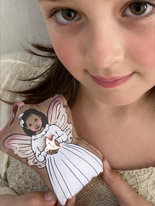 a little girl holding a ttoth fairy plush hanging decoration