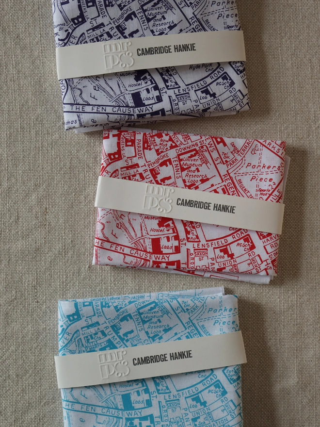 Three folded Mr.PS Cambridge map hankies to show the colour options available: violet, red, and aqua