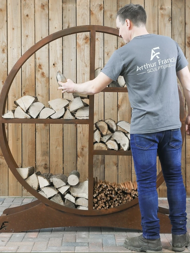 Oakham Log Store, man filling log store with wood. 