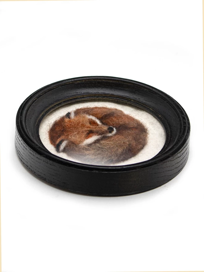 Oblique view of a needle-felted fox picture in a round black frame
