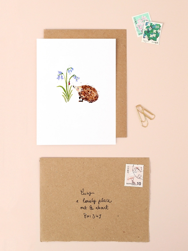 A charming illustration of a small hedgehog nestled among delicate bluebell flowers, capturing the essence of spring. The hedgehog's spiky fur and the bell-shaped blooms are rendered in soft, pastel hues, creating a serene and nature-inspired scene. The design is minimalist and heartwarming, perfect for conveying a message of kindness or appreciation.