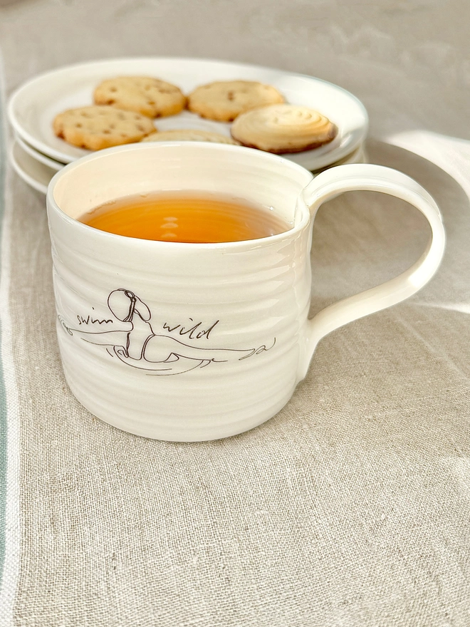 Handcrafted porcelain ‘Swim Wild’ mug – unique ceramic coffee cup for swimmers, nature lovers, and outdoor adventurers.