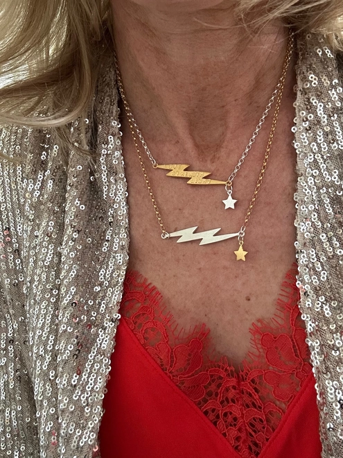 model wearing a sterling silver chain with personalised gold electric bolt charm and a small silver star, and a gold chain with silver electric bolt and small gold star
