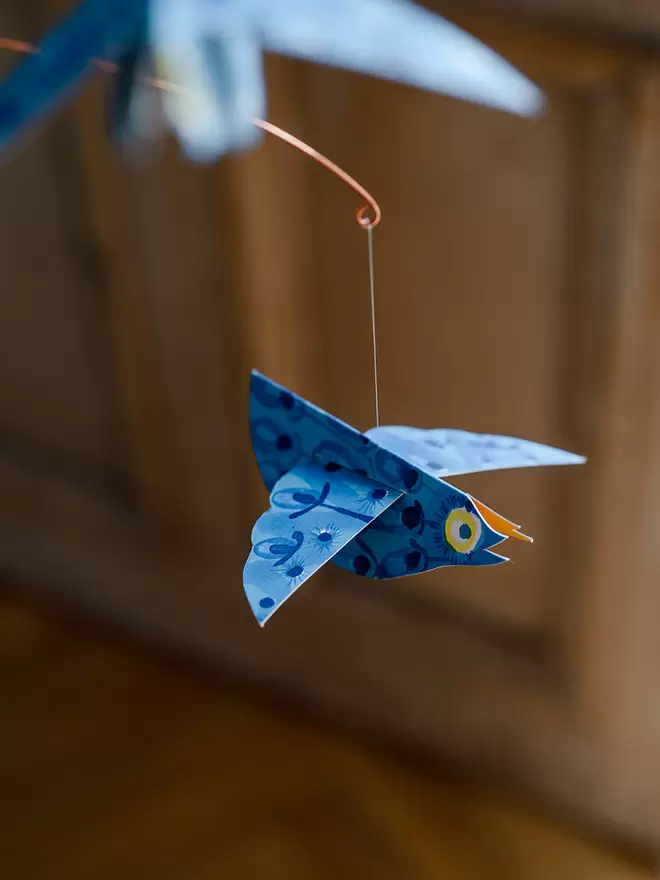 Blue patterned paper bird with a yellow eye. Photo Zoe Barrie.