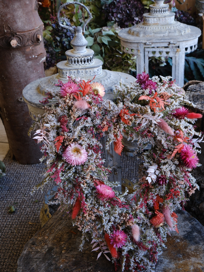 Pretty in pink heart wreath. A heart shaped wreath with pink dried flowers resting on a metal lantern