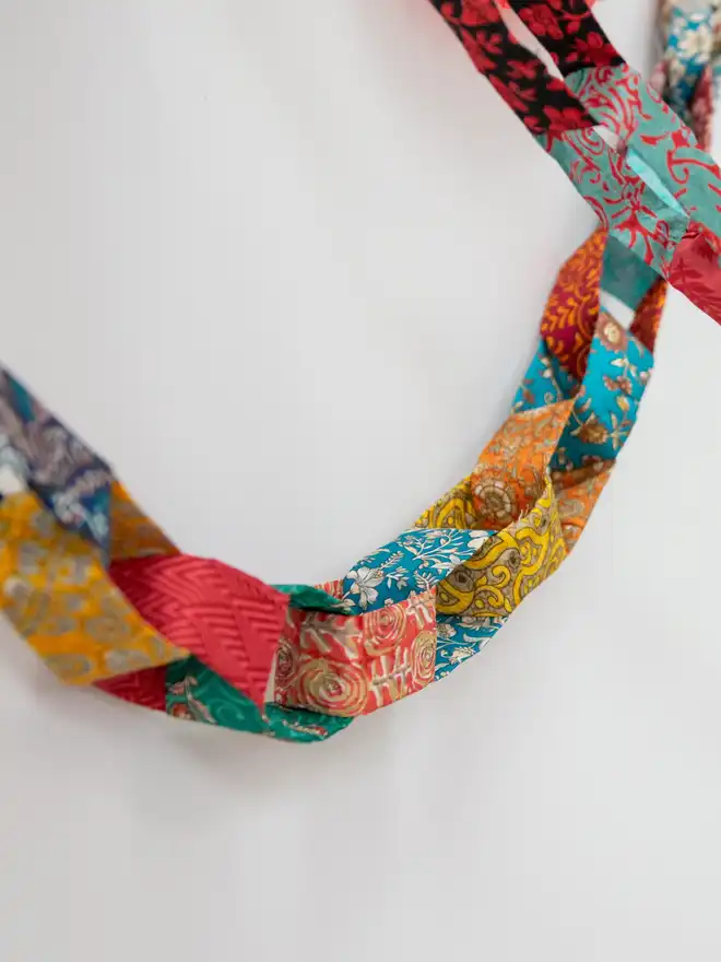 Colourful fabric chain against a white wall