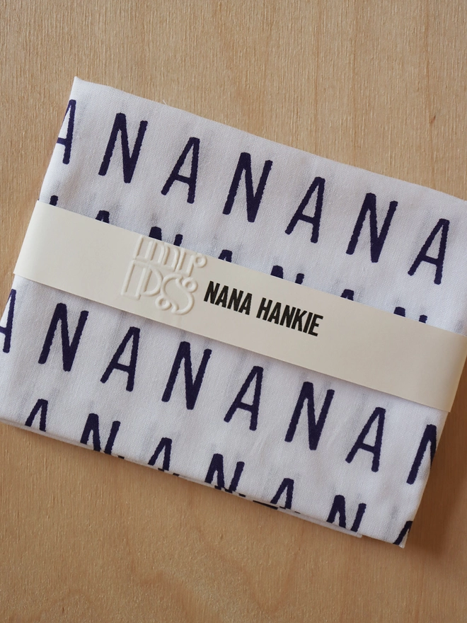 A folded Mr.PS NANA Hankie on a wooden table