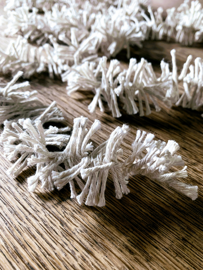 Close up of white Plain Cotton Strinsel (plastic free string tinsel) on an oak background