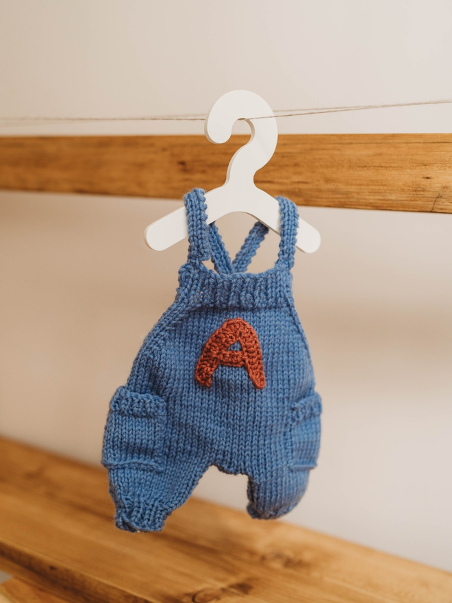 hand knitted personalised blue teddy bear dungarees on toy hanger