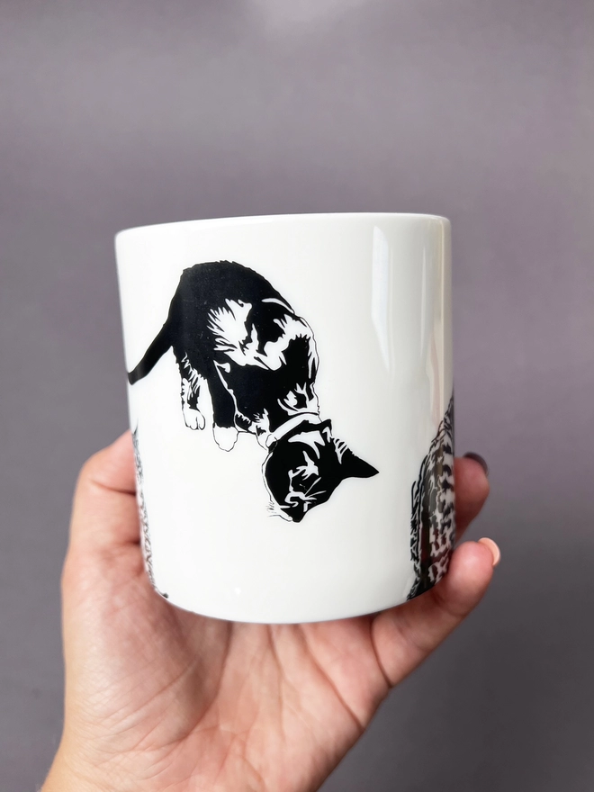 Cute kitten peeking at the bottom of the mug