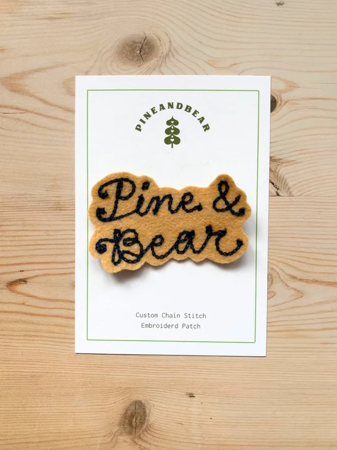 Custom chain stitch patch in biscuit and navy on a white presentation card