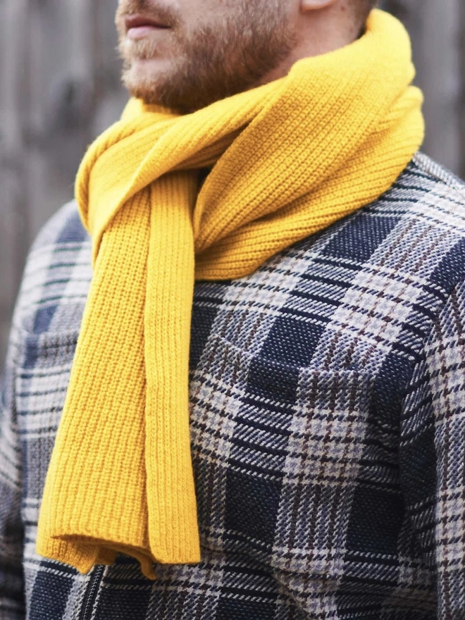 Lambswool Ribbed Scarf, a man wearing a colourful ribbed scarf outdoors. 