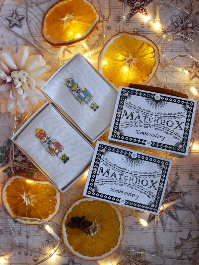 Embroidered nutcrackers displayed in their matchboxes.  Surrounded by dried orange slice decorations and fairy lights.