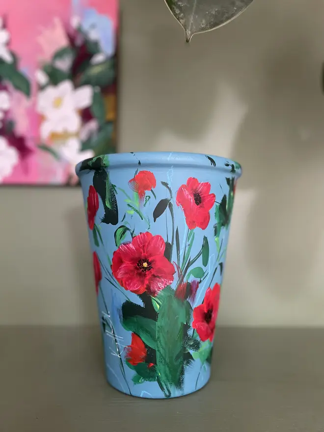 hand painted terracotta floral plant pot air force blue background with rich red poppies. 