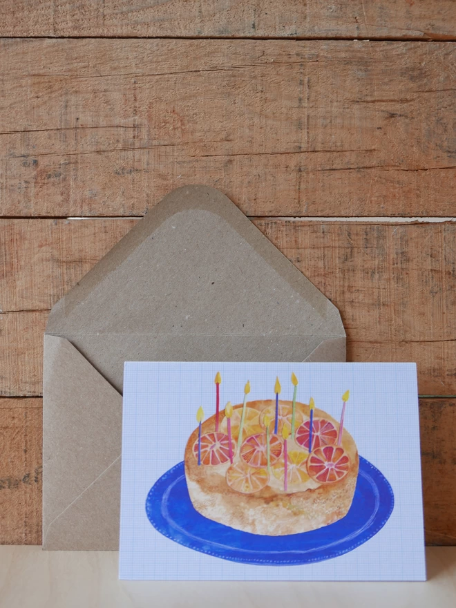 The Orange Upside Down Birthday Cake Card next to its brown envelope with front of card visible