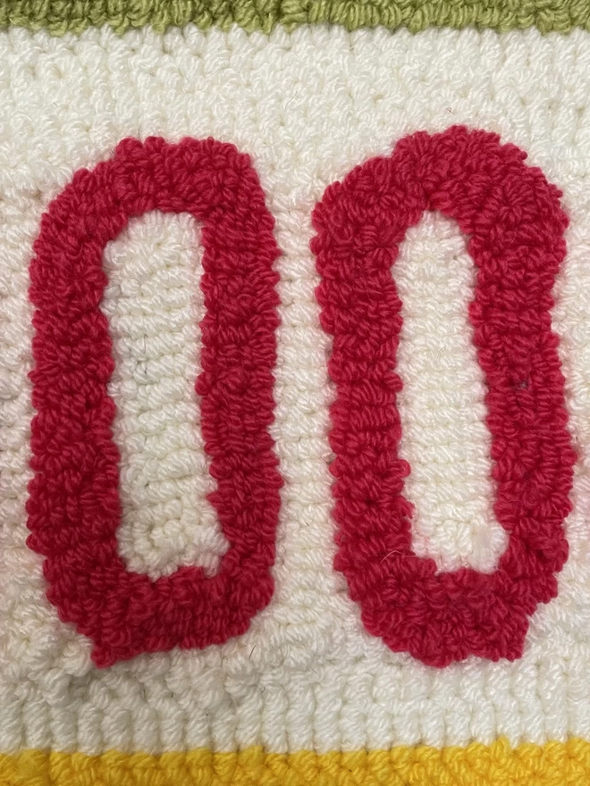 close up of two pink "OO" on cream wool loop background