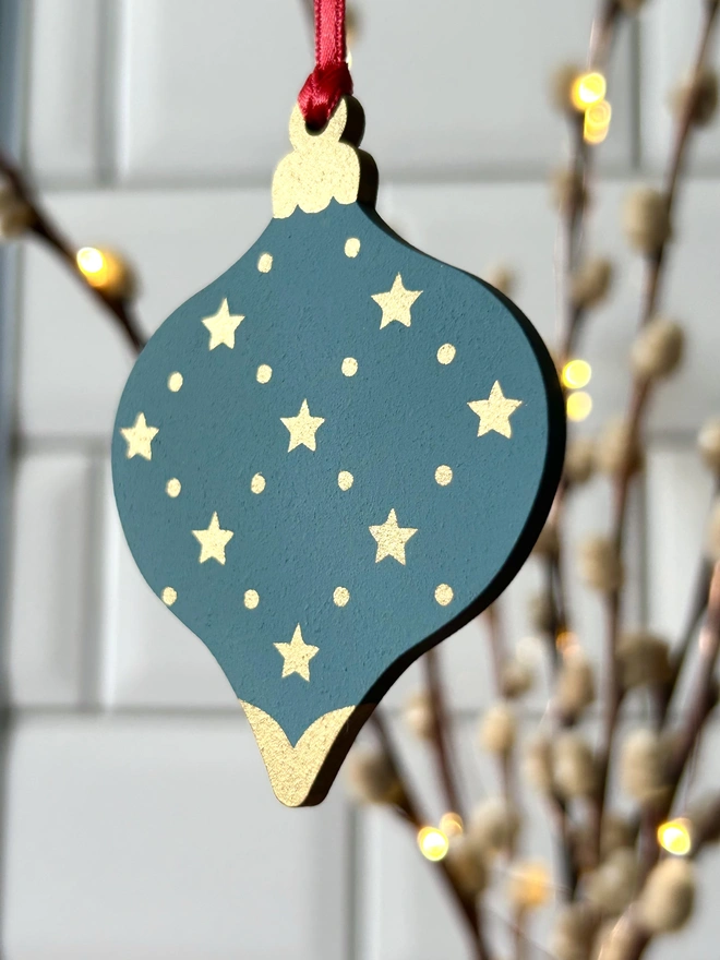 The reverse side of laser cut wooden bauble shapes which have been hand painted with one christmas candle design and one with a festive bell design. Using blue, yellow, green, red and gold paint.