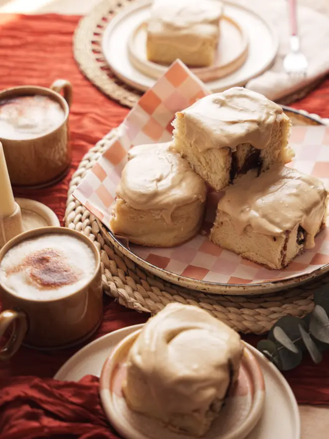 Latte Cinnamon buns stacked up on a plate with luscious coffee frosting on top