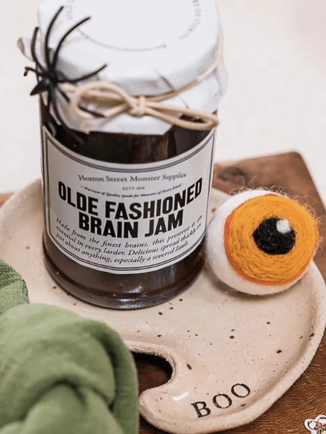 ghost shaped plate holding a jar of jam and a cotton eye ball 