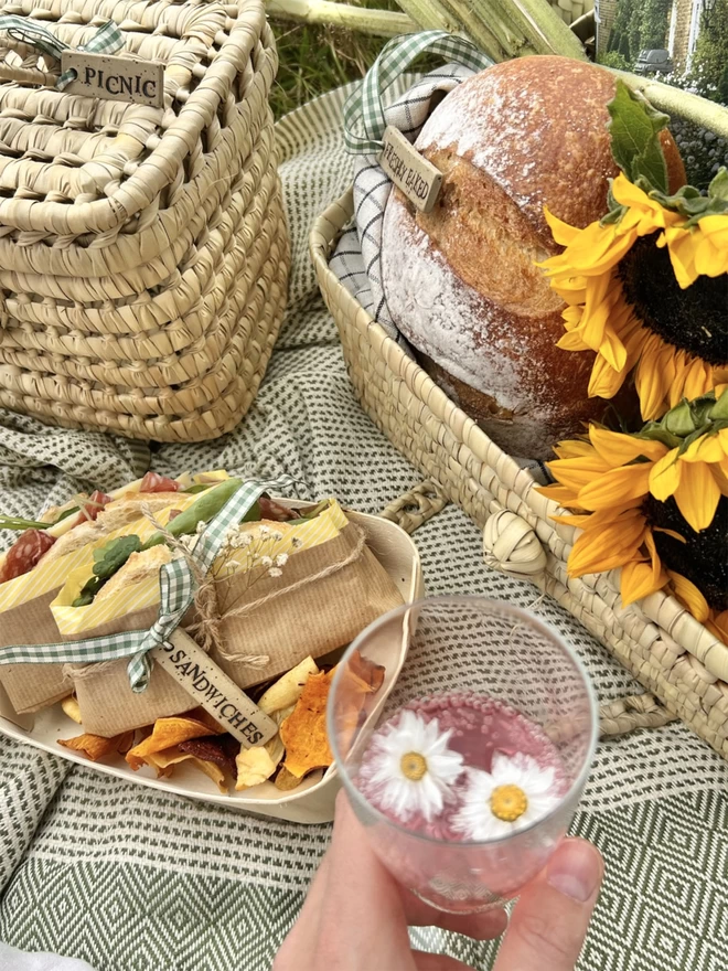 picnic scene with woven baskets and a tray of sandwiches