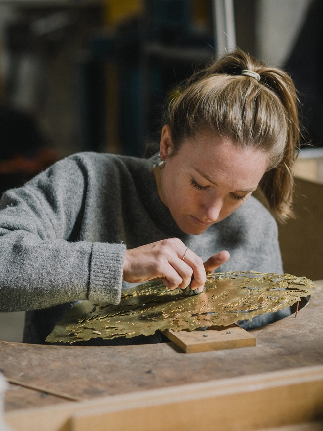 Holly in the workshop sanding the metal wall map