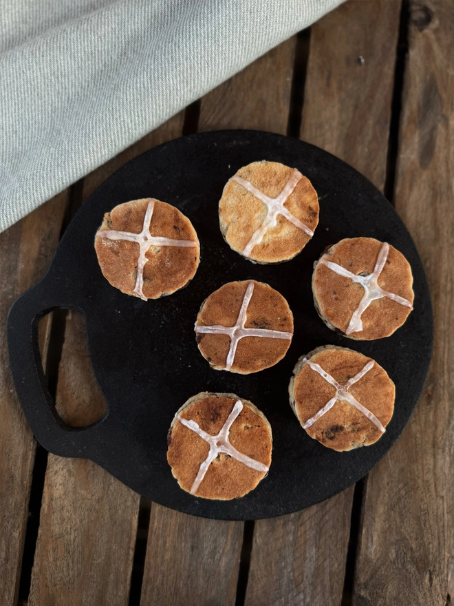 6 Hot Cross Bun Welsh Cakes on a black bakestone with a wood background